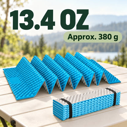 Folded sky-blue and silver camping mat resting on an outdoor table.